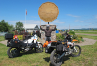 man standing in front of big loonie with 2 motorcycles